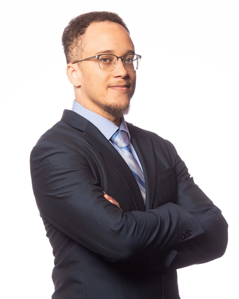 Portrait of Collin Joseph in a navy suit with arms crossed